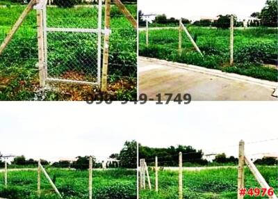 Empty land plot with fence and gate adjacent to a paved road