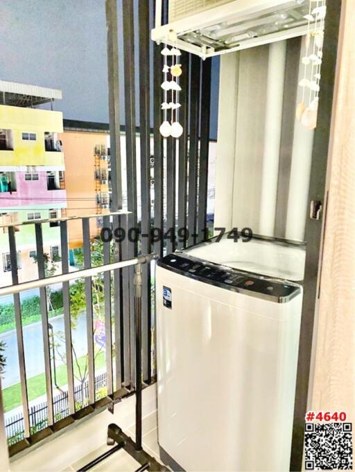 Compact balcony with a washing machine and a view of adjacent buildings