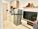 Modern kitchen with integrated living space featuring refrigerator and wall-mounted TV