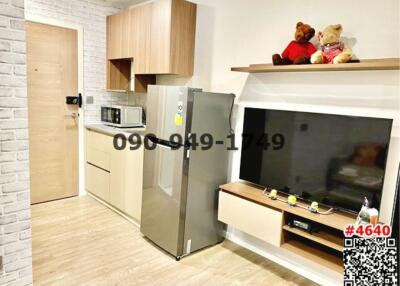 Modern kitchen with integrated living space featuring refrigerator and wall-mounted TV