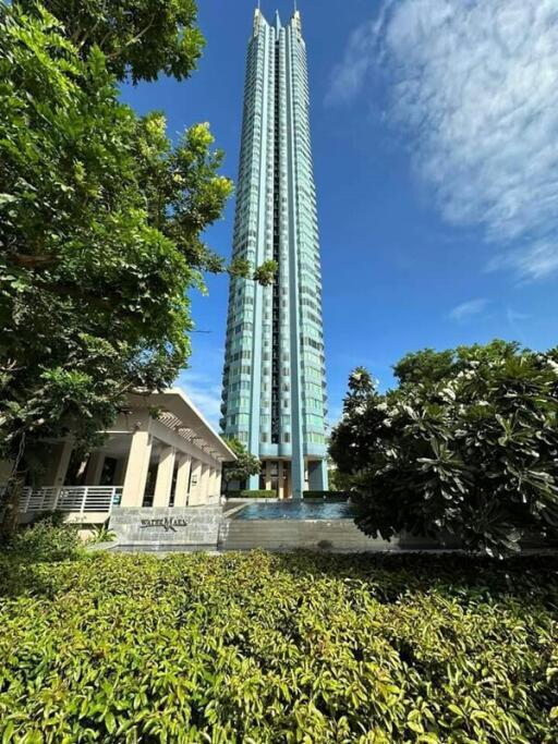 Tall modern residential skyscraper with green landscaping in the foreground