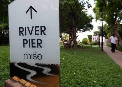 River Pier signpost with walking path and greenery