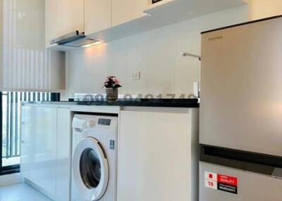 Modern kitchen with white cabinetry, washing machine, and stainless steel refrigerator