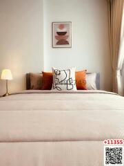 Cozy bedroom with a neatly made bed, decorative pillows, and framed artwork