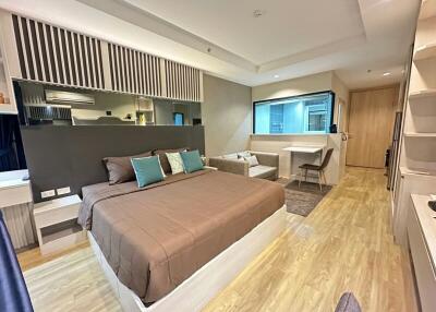 Modern bedroom with integrated workspace and open kitchenette
