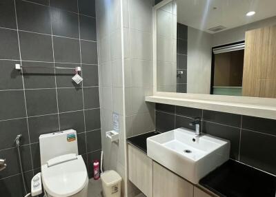 Modern bathroom with a wall-mounted sink, toilet, and tiled walls