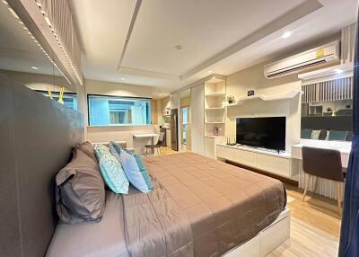 Modern bedroom interior with queen-sized bed and entertainment unit