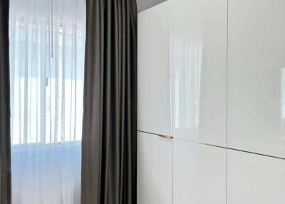 Modern bedroom with large white wardrobe and curtains