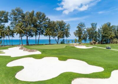 Lush green golf course by the beach with palm trees and clear skies