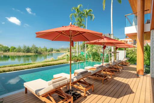 Luxurious poolside deck with loungers and umbrellas overlooking a scenic water body