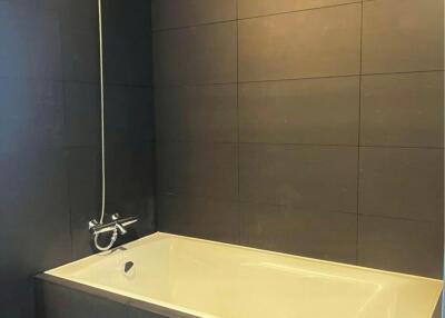 Modern bathroom with wall-mounted shower and dark tiles