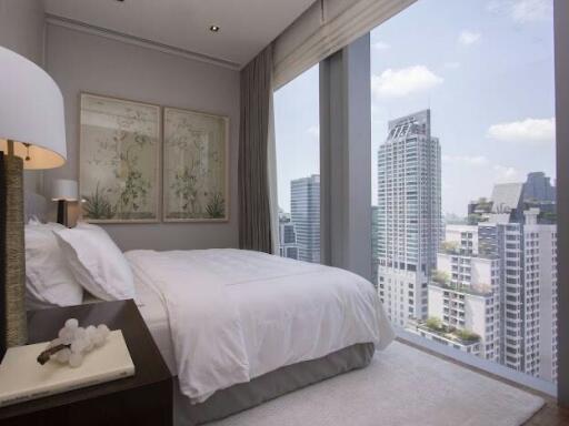 Modern bedroom with a large bed and floor-to-ceiling windows overlooking the city