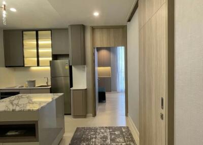 Modern apartment interior view showing the hallway, kitchen, and glimpse of the bedroom