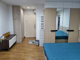 Modern bedroom interior with large mirrored wardrobe and hardwood flooring
