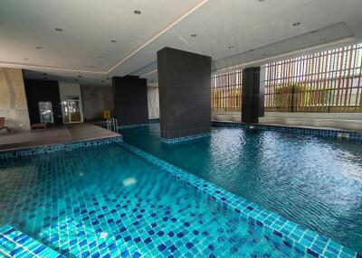 Luxurious indoor swimming pool with blue mosaic tiles and natural lighting
