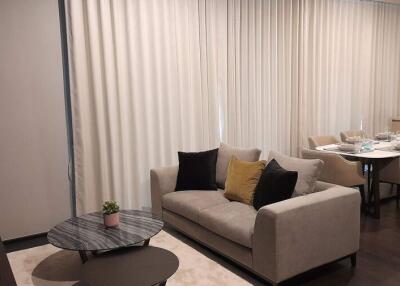 Elegant living room with neutral color sofa and a dining area in the background