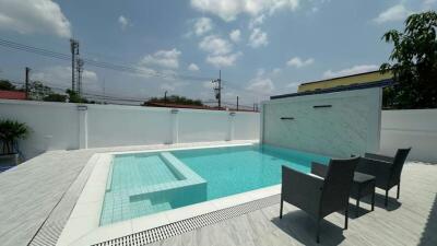 Private swimming pool with patio furniture under the clear sky
