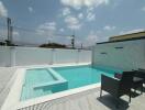Private swimming pool with patio furniture under the clear sky