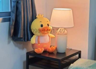 Cozy bedroom with a cute stuffed animal on a nightstand beside a small lamp