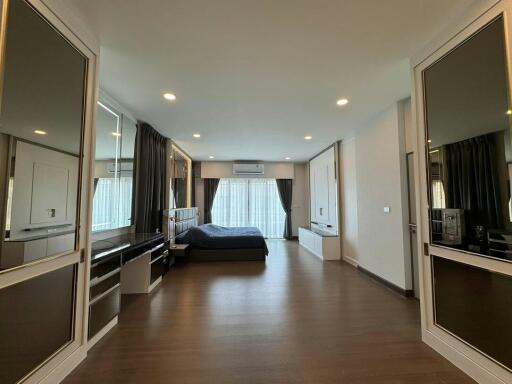 Spacious master bedroom with hardwood floors and modern furniture