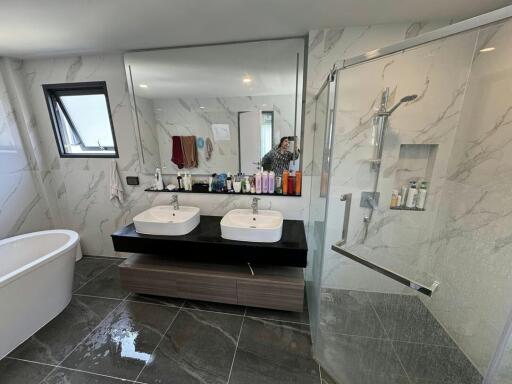 Spacious bathroom with dual sinks, marble tiles and glass shower