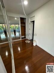Spacious bedroom with polished wooden floors and glass sliding door leading to balcony