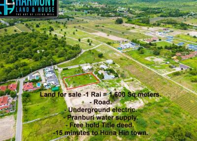 Aerial view of a land plot for sale with surrounding greenery and residential development