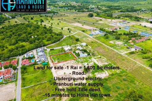 Aerial view of a land plot for sale with surrounding greenery and residential development