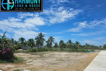 Spacious vacant land with clear blue sky and surrounding greenery