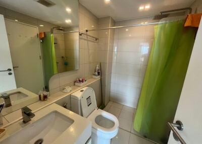 Bright tiled bathroom with shower, washbasin, and washing machine