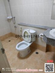 White tiled bathroom with toilet and sink