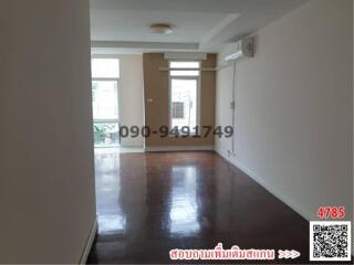 Spacious empty living room with glossy hardwood flooring and ample natural light