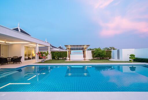 Modern residential outdoor swimming pool with patio area during twilight