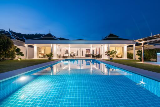 Luxurious night view of an outdoor swimming pool with a villa in the background