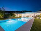 Elegant outdoor pool area with well-lit house and garden at dusk