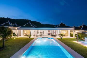 Luxurious house exterior with illuminated swimming pool at twilight