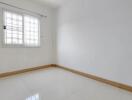 Bright empty bedroom with large window and tiled flooring