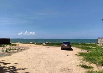 Unpaved coastal land with a parked car and sea view under a clear blue sky