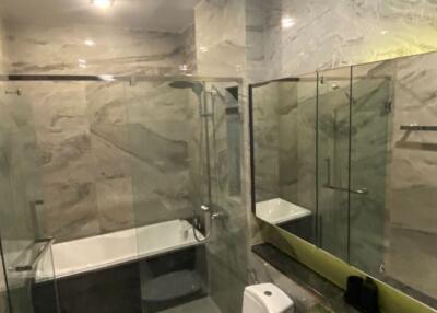 Modern bathroom with marble walls and glass shower enclosure