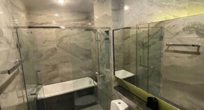 Modern bathroom with marble walls and glass shower enclosure