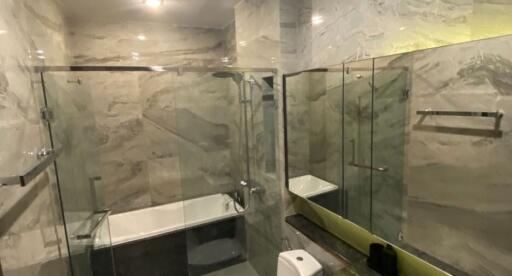 Modern bathroom with marble walls and glass shower enclosure