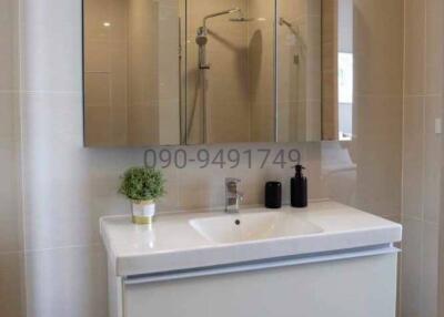 Modern bathroom interior with clean design, featuring a wall-mounted sink, mirror, and walk-in shower