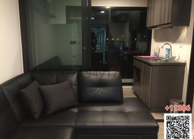 Compact living room with adjacent open kitchen at night