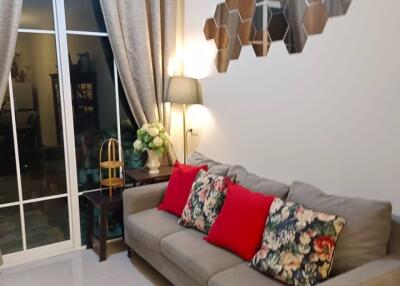 Cozy living room with a modern gray sofa, decorative pillows, and stylish wall-mounted lighting