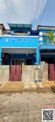 Bright blue two-story residential building with front gates and balcony