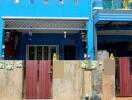 Bright blue two-story residential building with front gates and balcony