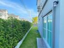 View of a residential building exterior showcasing a well-maintained lawn and side pathway