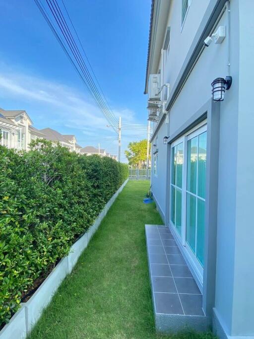 View of a residential building exterior showcasing a well-maintained lawn and side pathway