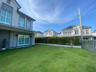 Suburban two-story house with spacious front lawn under a clear blue sky