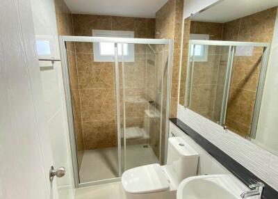 Modern bathroom with clear glass shower enclosure, large mirror, and stylish tiling